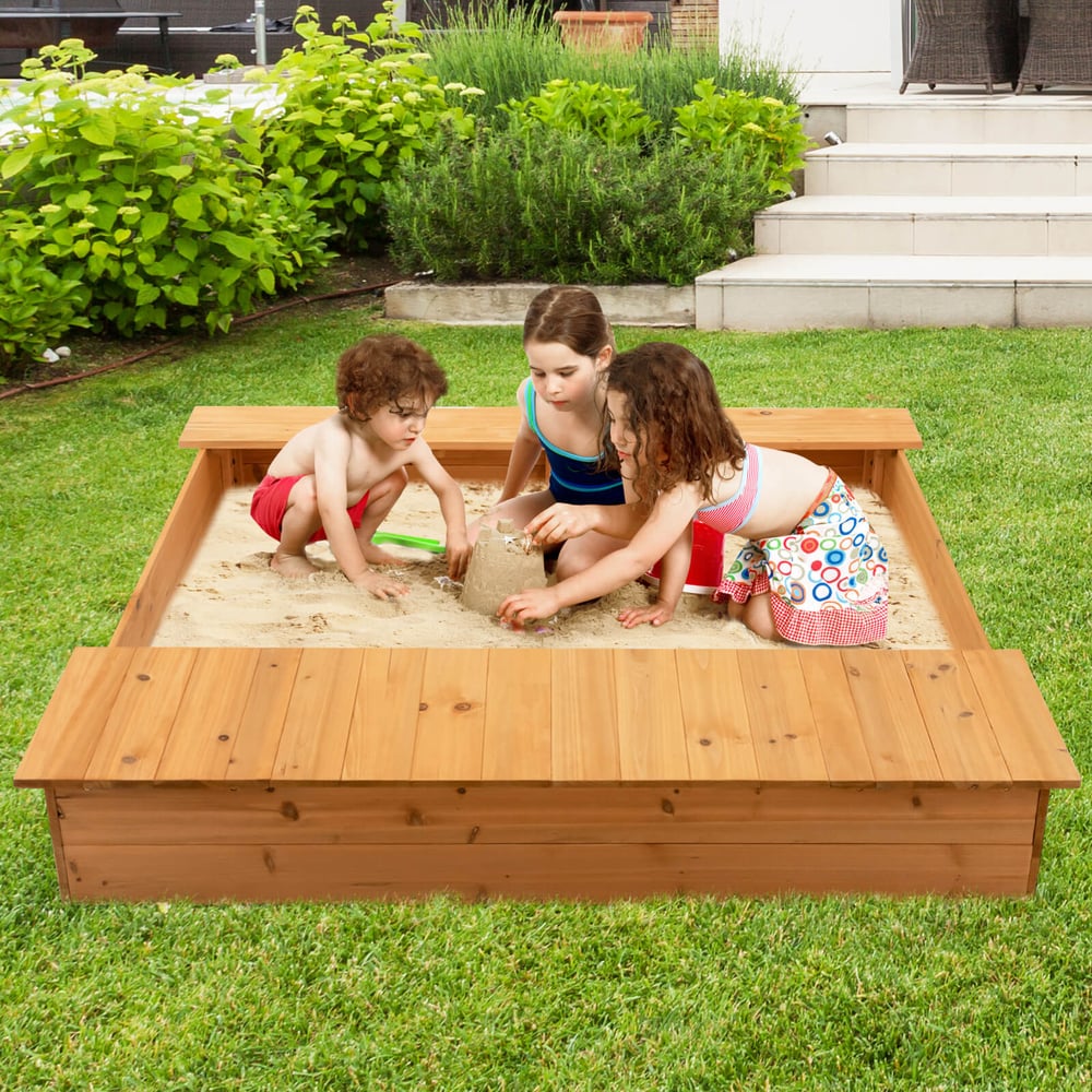 Three children playing in the wooden sandbox with integrated seating in a garden setting