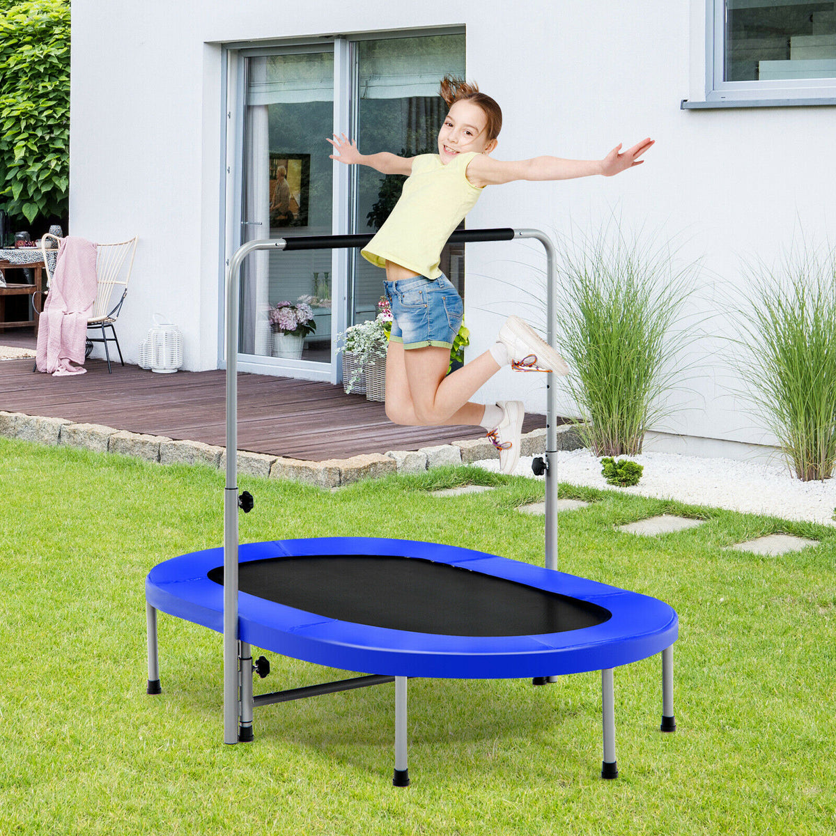 A young girl jumping on the blue fitness trampoline in a garden setting