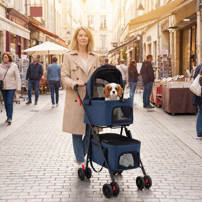 Woman pushing the blue double pet stroller with a dog in the top carrier down a street