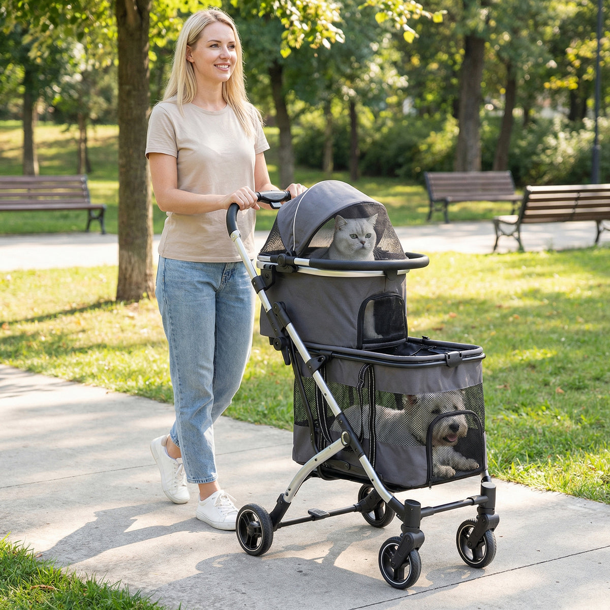A woman pushes the dog stroller with two pets in a park on a sunny day