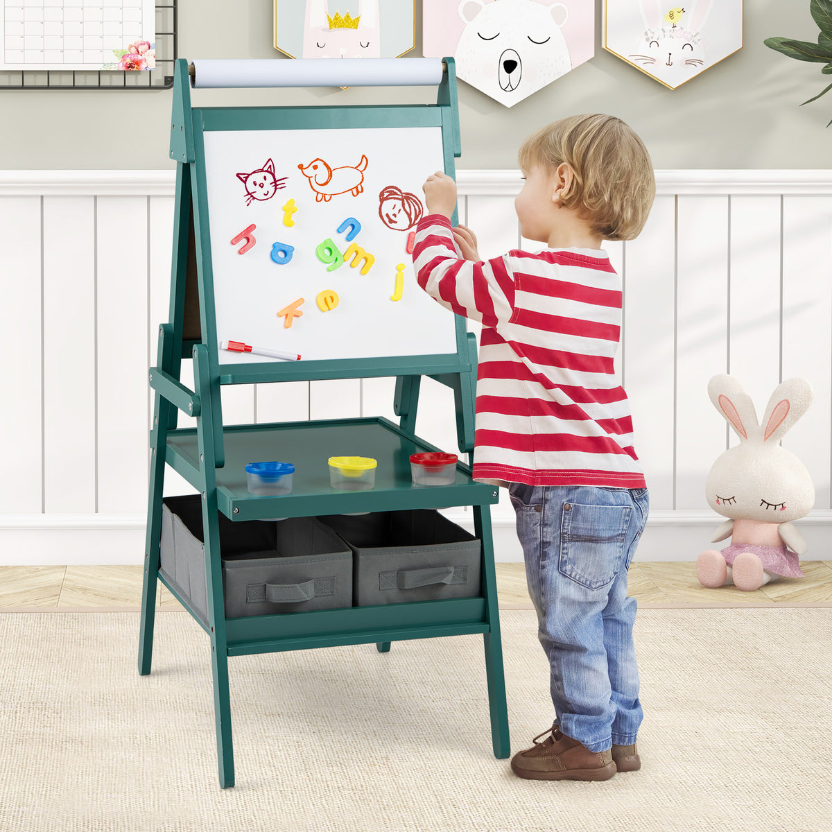 The art easel being used by a young child to place magnetic letters on the whiteboard