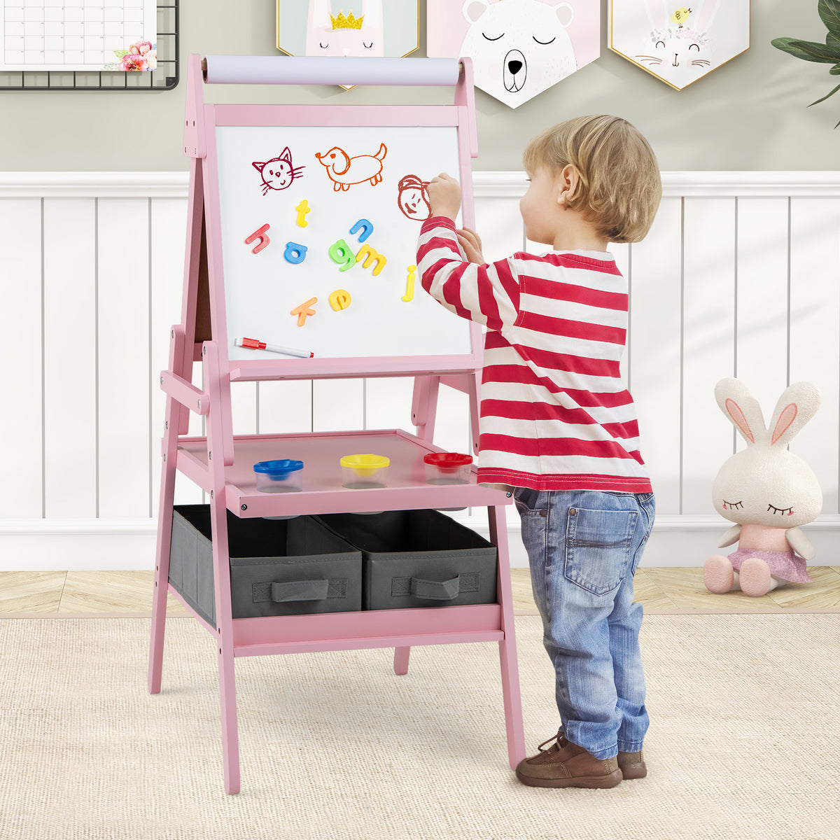 Young boy drawing on the magnetic whiteboard side of the pink kids easel