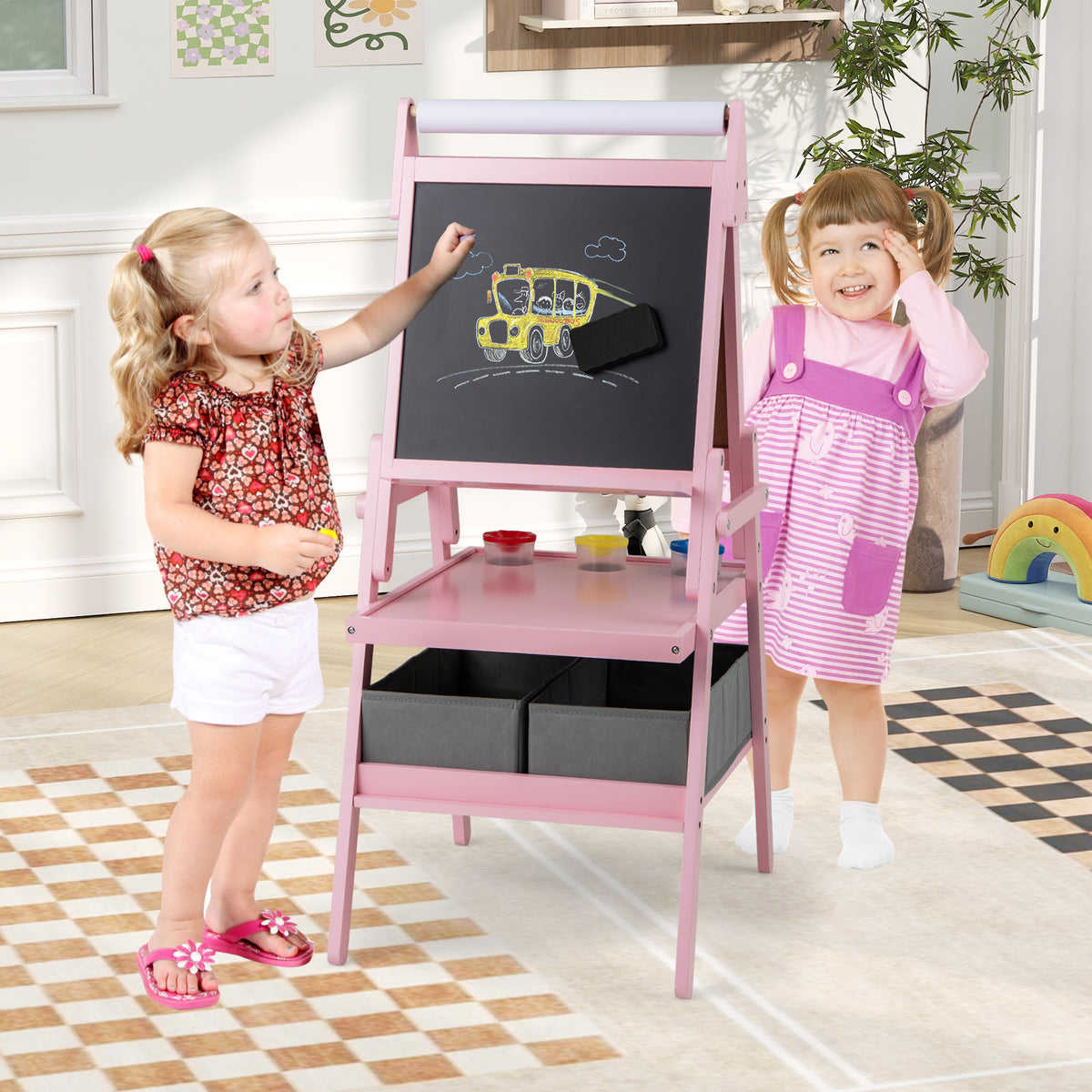 Pink art easel with a child drawing on the magnetic whiteboard side, with a second child watching