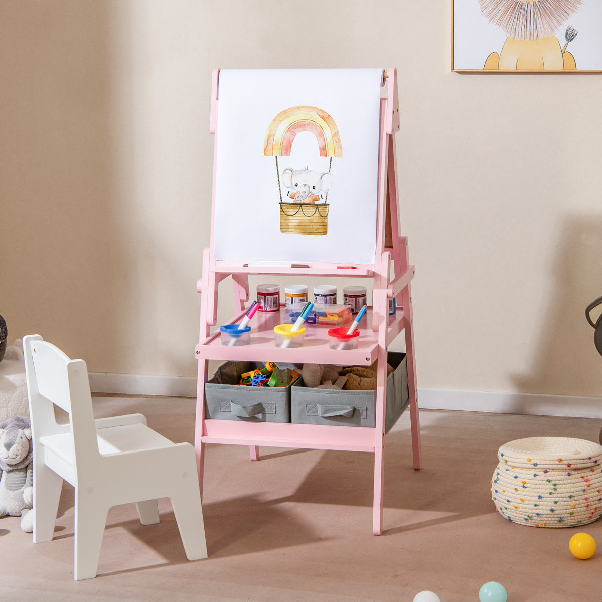 Pink art easel with a drawing of an elephant on paper, surrounded by art supplies and a child's chair