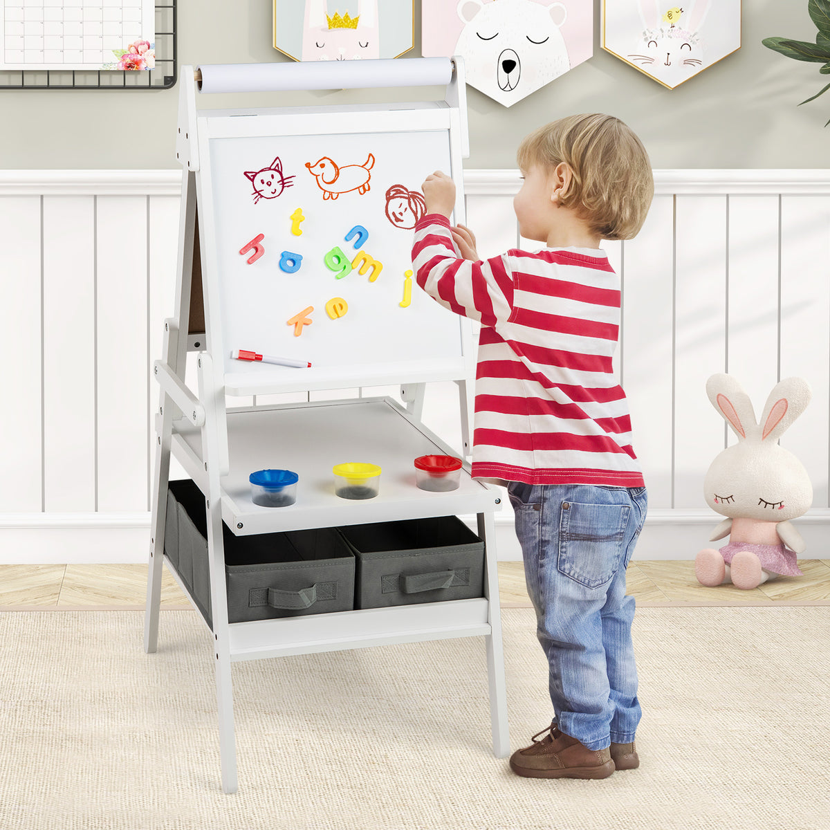 A young boy drawing on the magnetic whiteboard side of the kids art easel