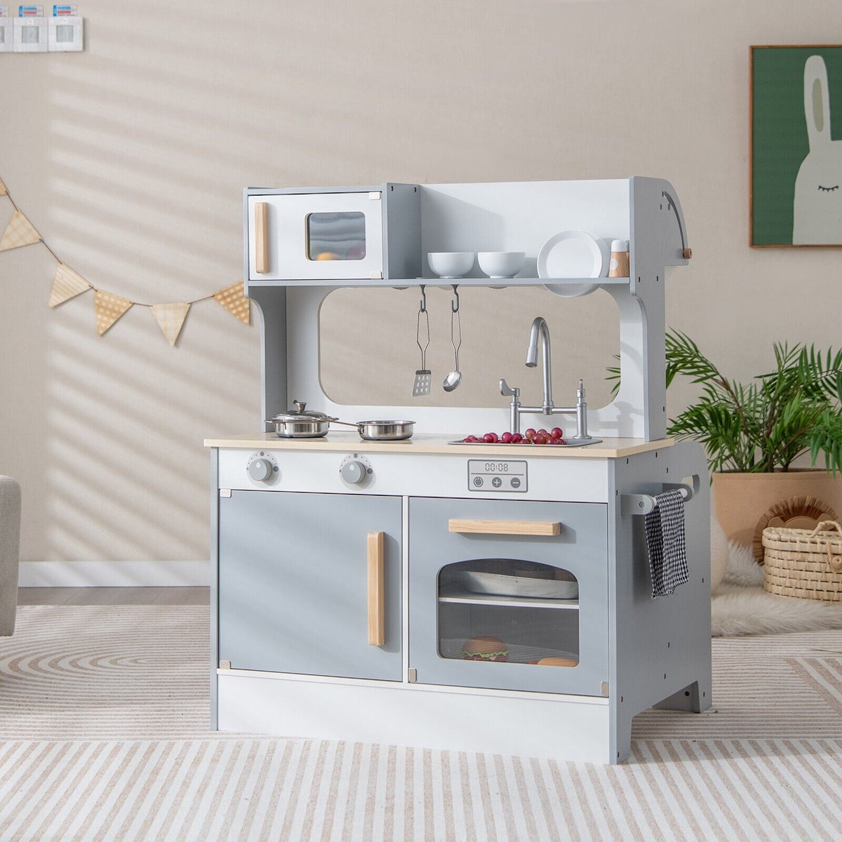 The grey and white play kitchen set is shown in a room with a child playing