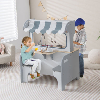 Two children play at the grey and white play kitchen set with seating