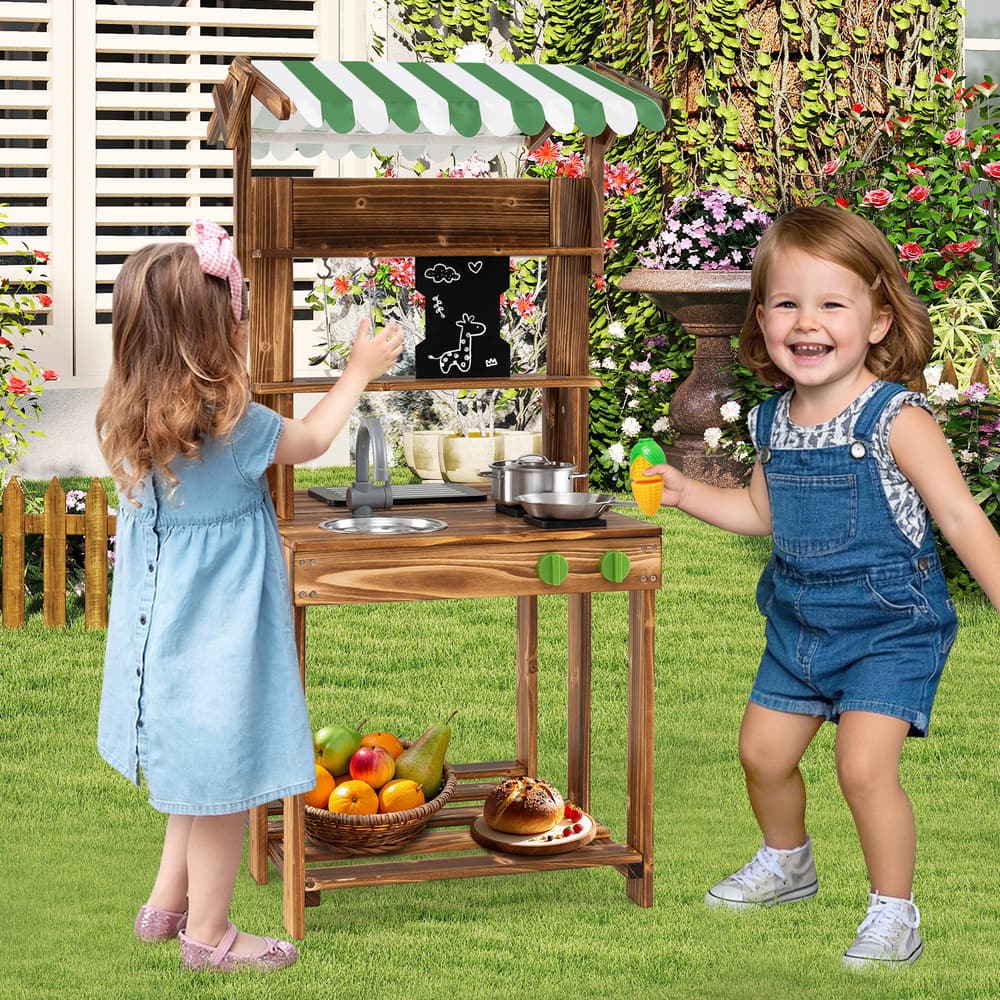 Two happy children playing with the wooden kitchen set in a sunny garden