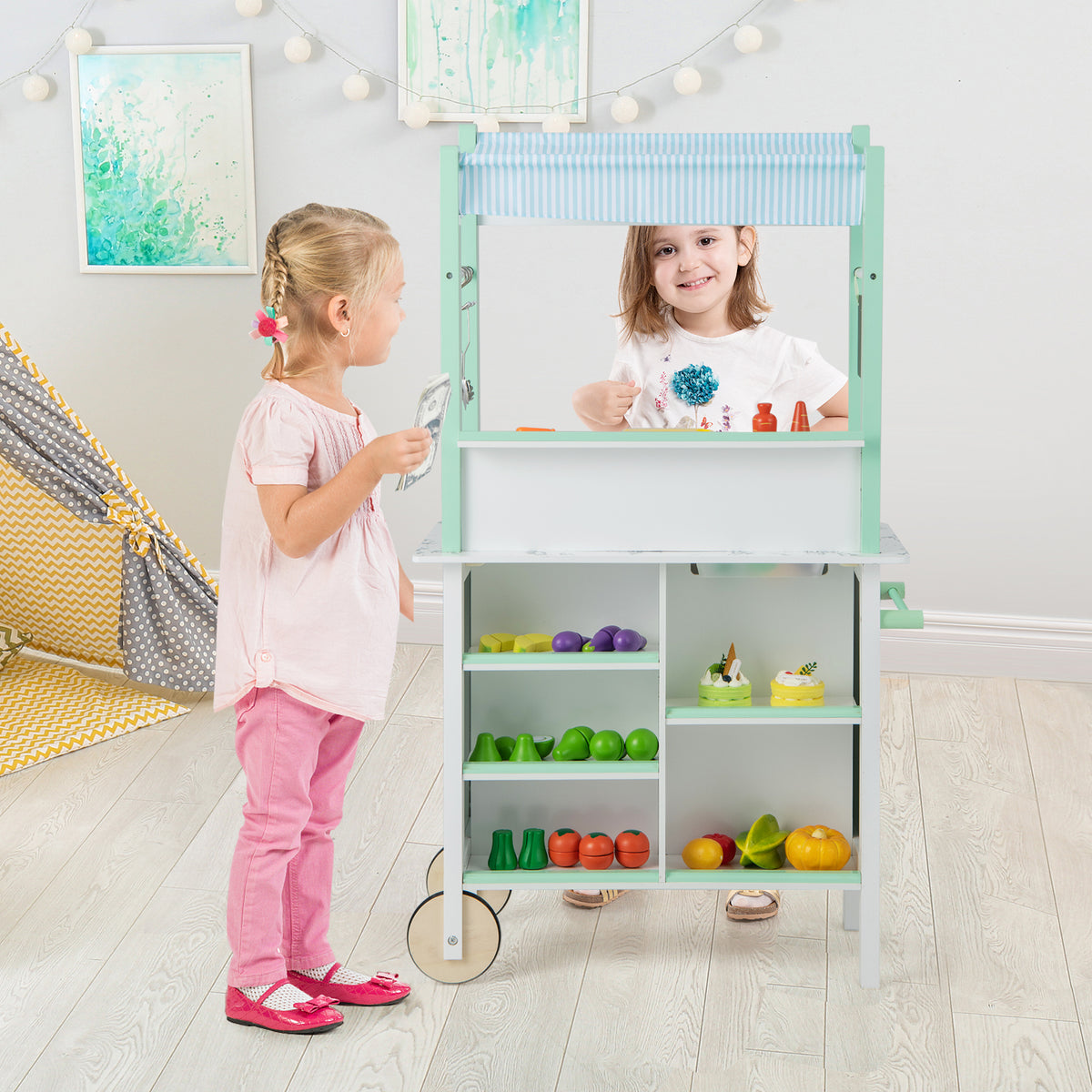 Children interacting with the green and white play kitchen set in a room