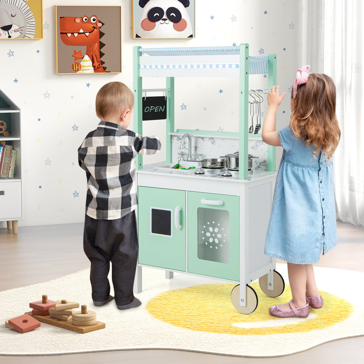 Children playing with the green and white play kitchen set in a room