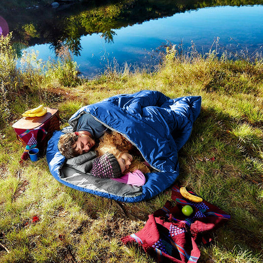 Couple sleeping in the blue double sleeping bag outdoors by a lake