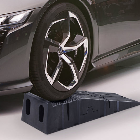 A black plastic car ramp being driven onto by a car wheel