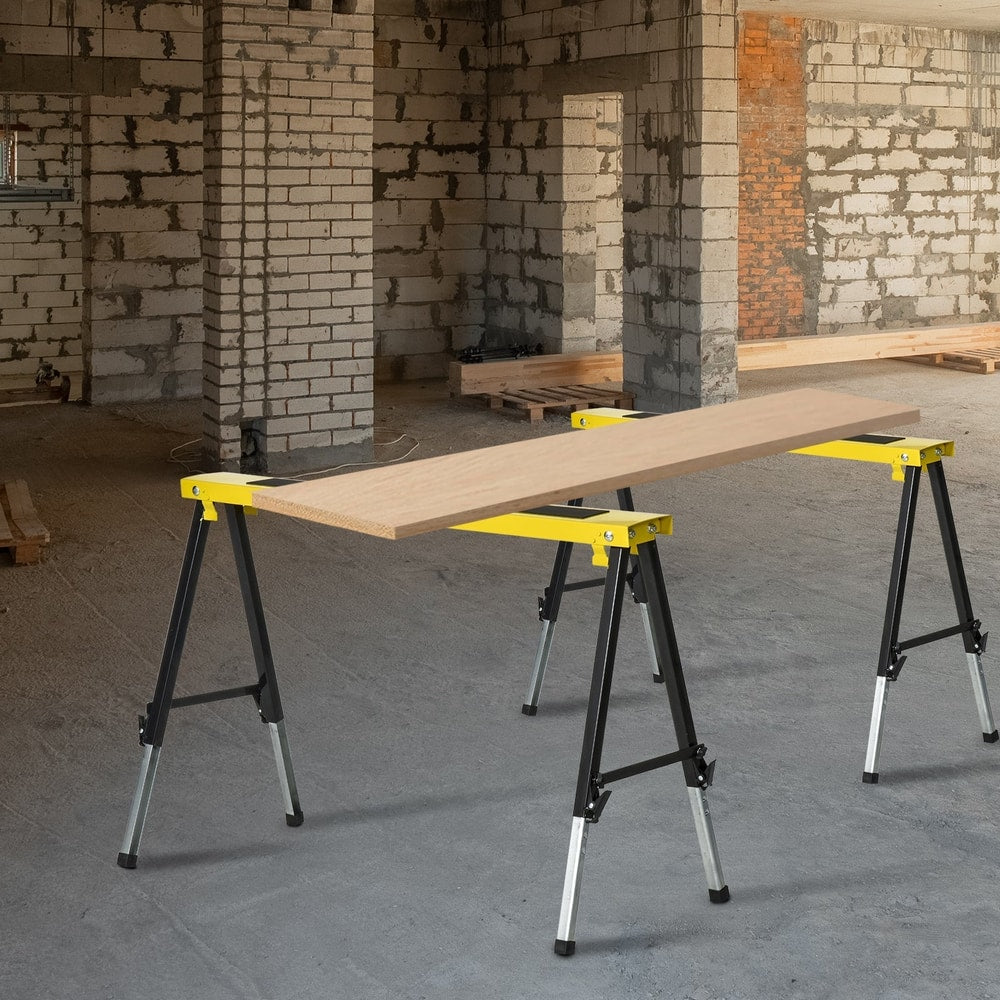 Two yellow and black metal trestle stands being used as a workbench in a construction site