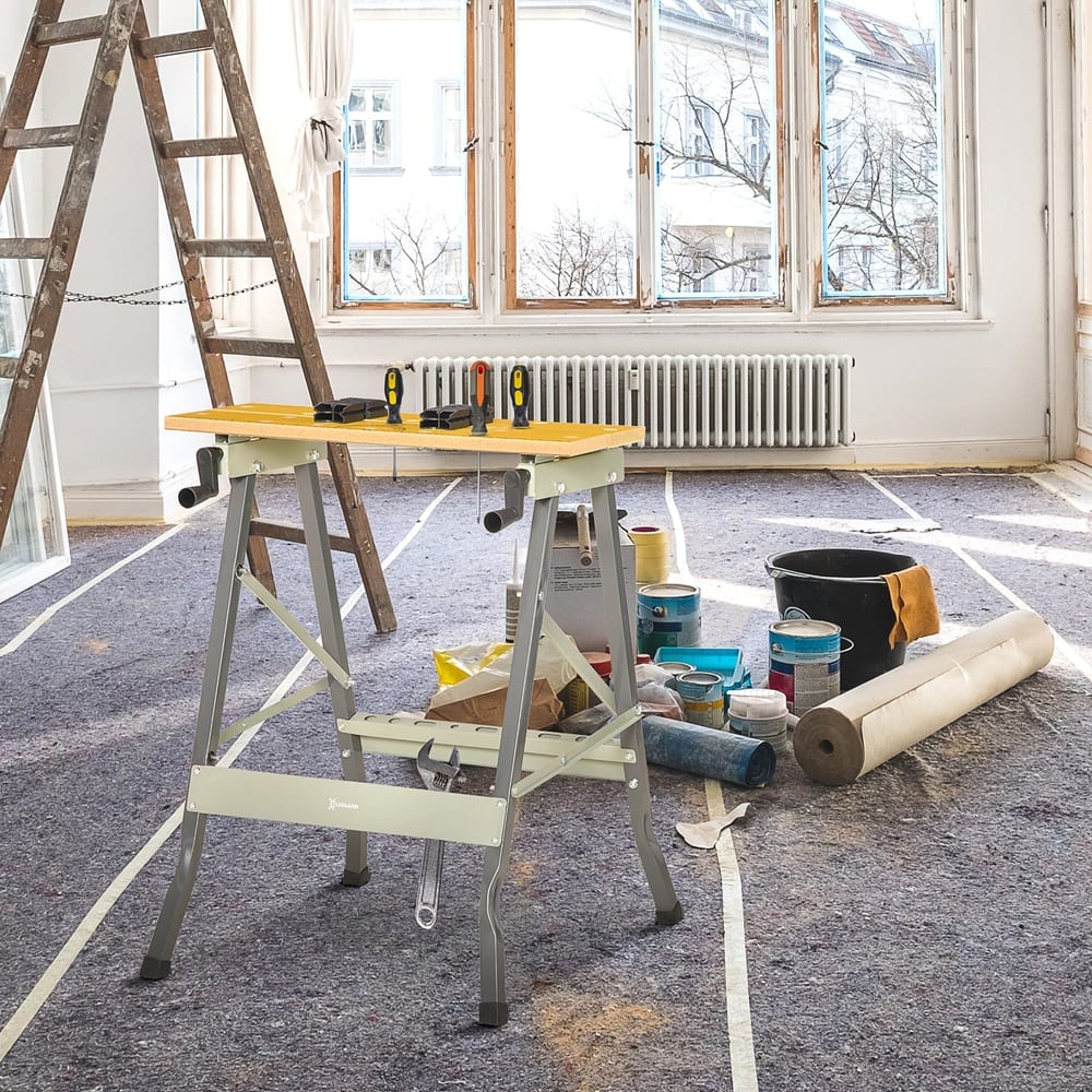 The grey 4-in-1 work bench is set up in a room with decorating supplies and a ladder nearby