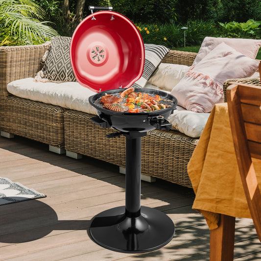 The outdoor grill with its lid open cooking food on a wooden patio with garden furniture