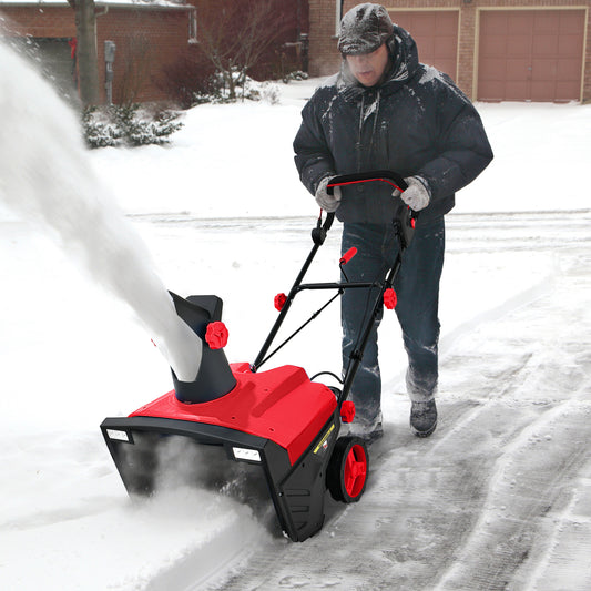 The garden tool in use by a person clearing a snowy driveway with the chute throwing snow aside