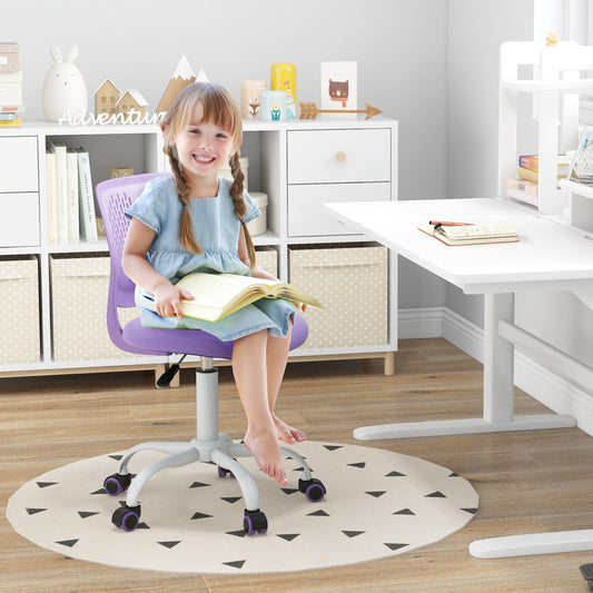 A young girl sits on the purple kids chair at a desk, reading a book