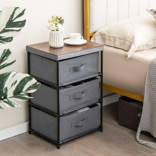 Grey fabric storage organizer tower unit with wood effect top next to a bed