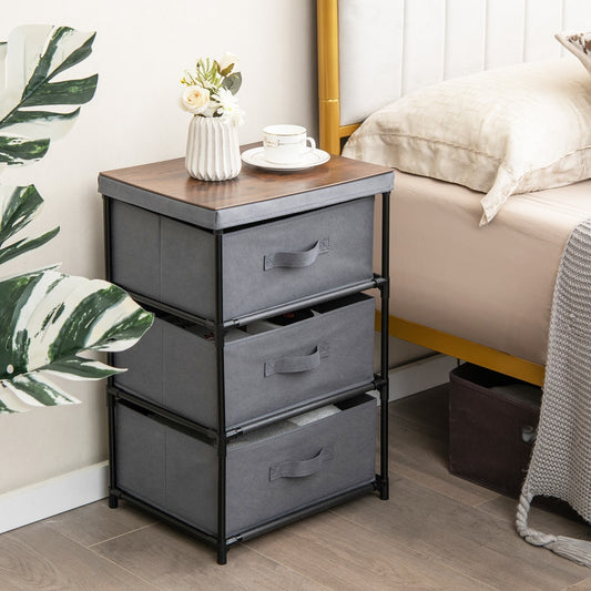 The grey fabric storage organizer tower unit with a wood-effect top placed next to a bed