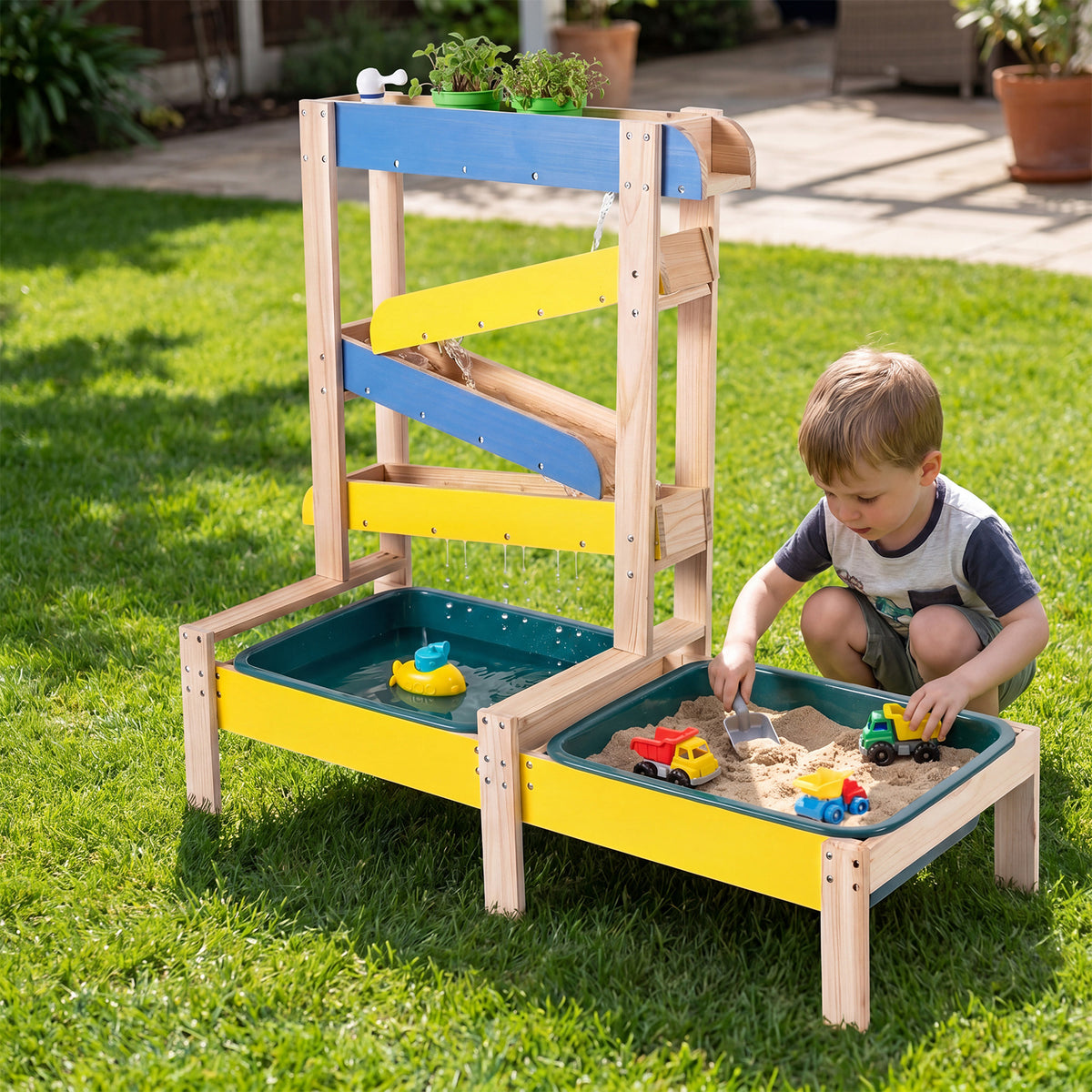 Boy playing with sand and toys in the activity table in the garden