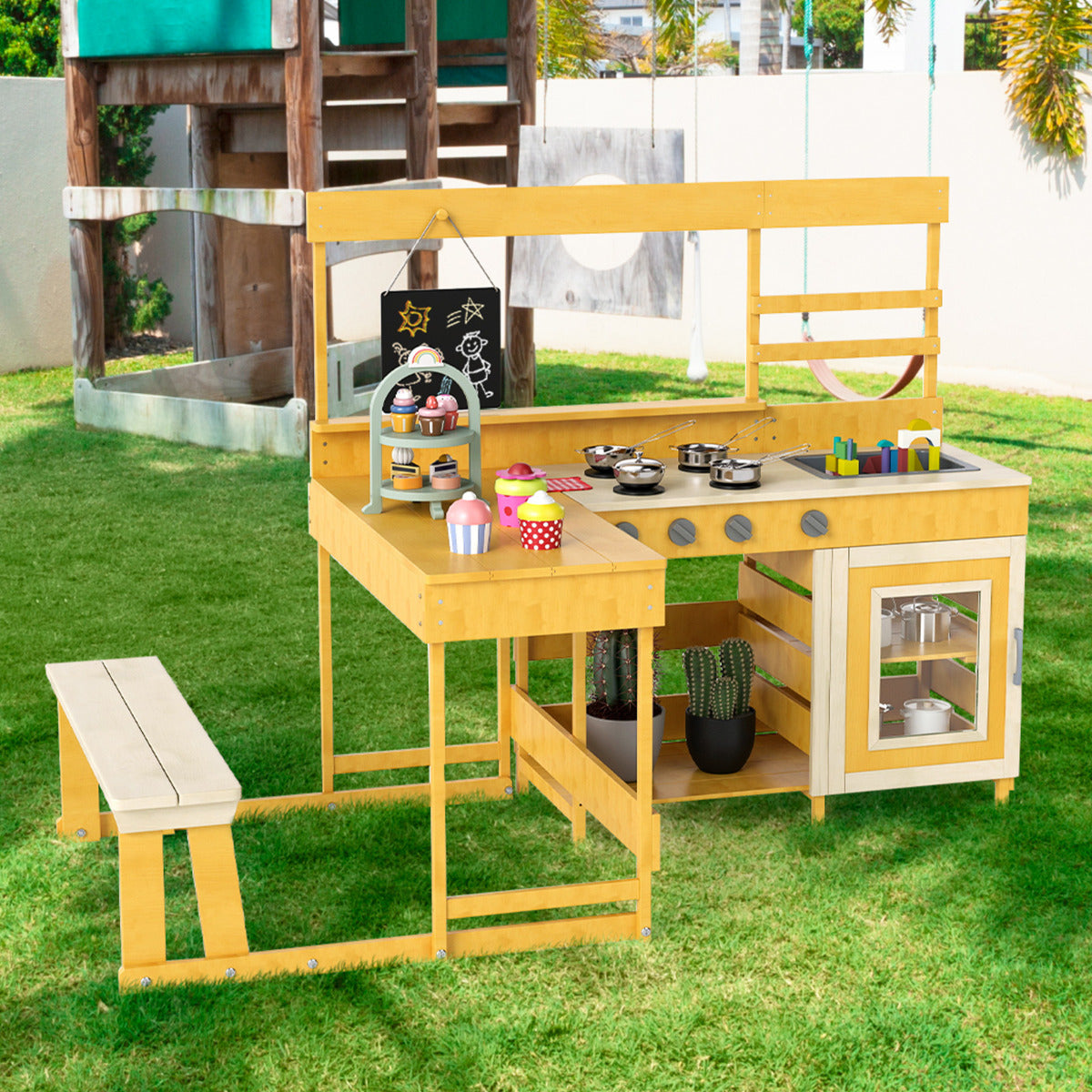 The natural wood mud kitchen with picnic table set up in a garden next to a climbing frame