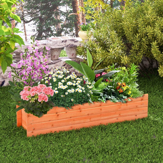 The wooden planter box sits on green grass surrounded by plants and a stone wall