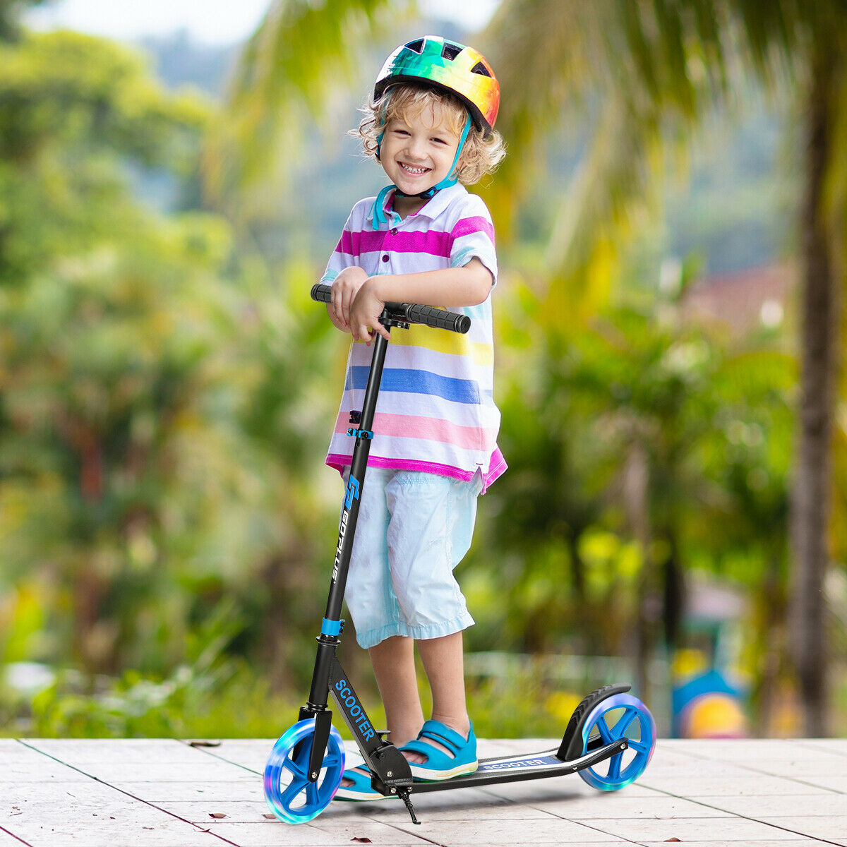 A young child smiling while standing on the blue kick scooter with LED wheels