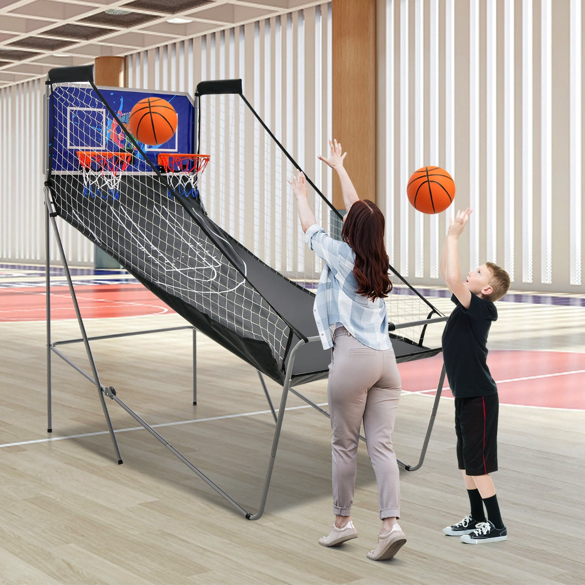 A boy and a woman playing the game room basketball arcade
