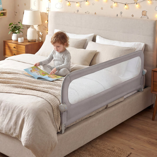 The foldable bed rail in use on a bed with a young child sitting up and reading a book
