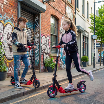 Two young people riding red kick scooters on a city pavement