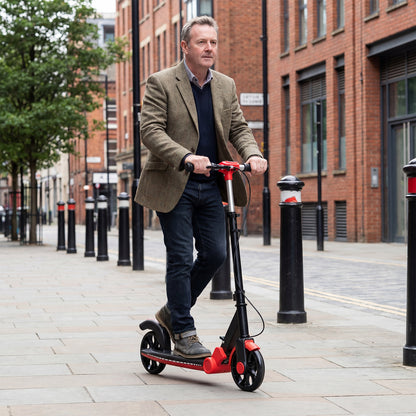 The red kick scooter being ridden by a man on a city street
