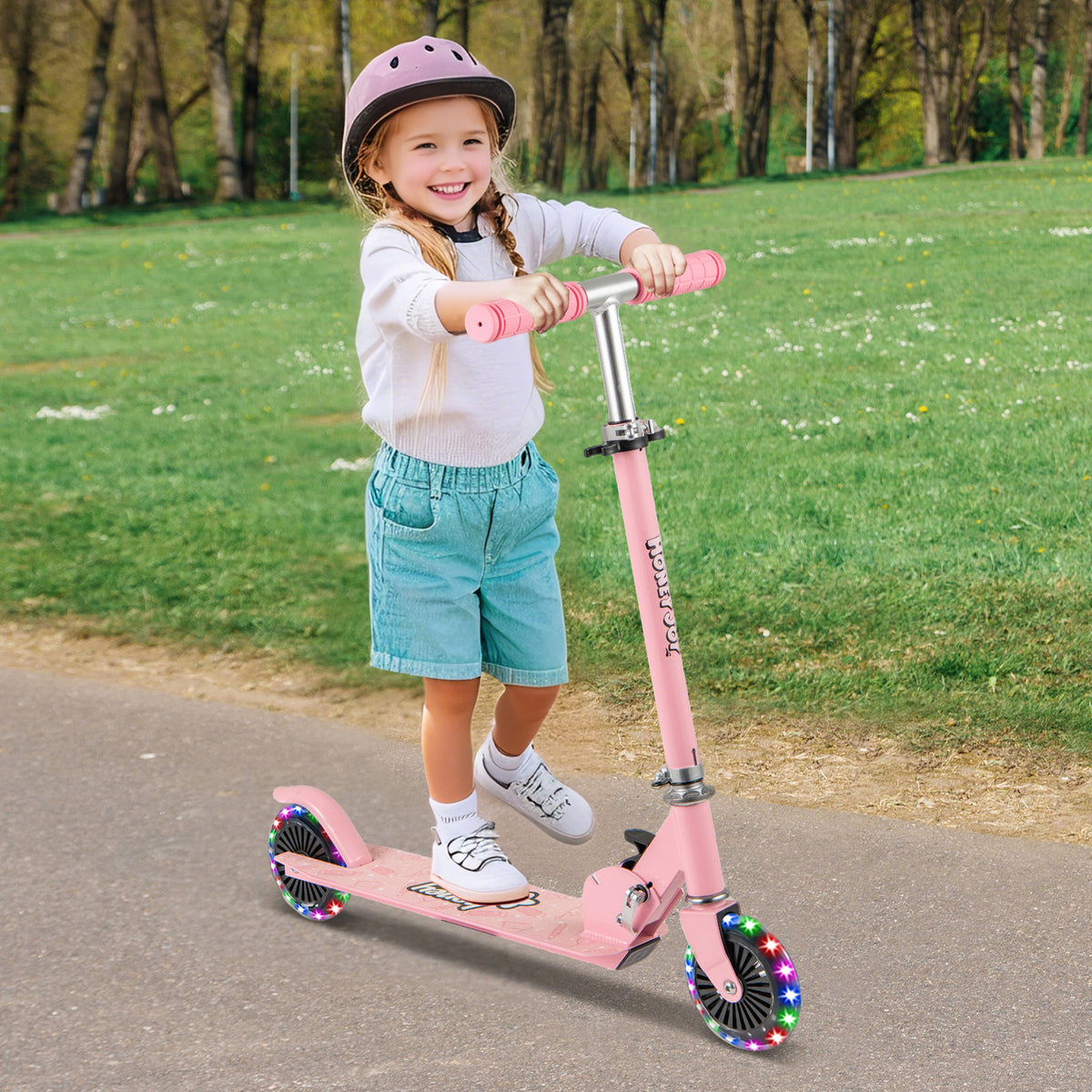 A smiling girl riding a pink scooter with light-up wheels in a park