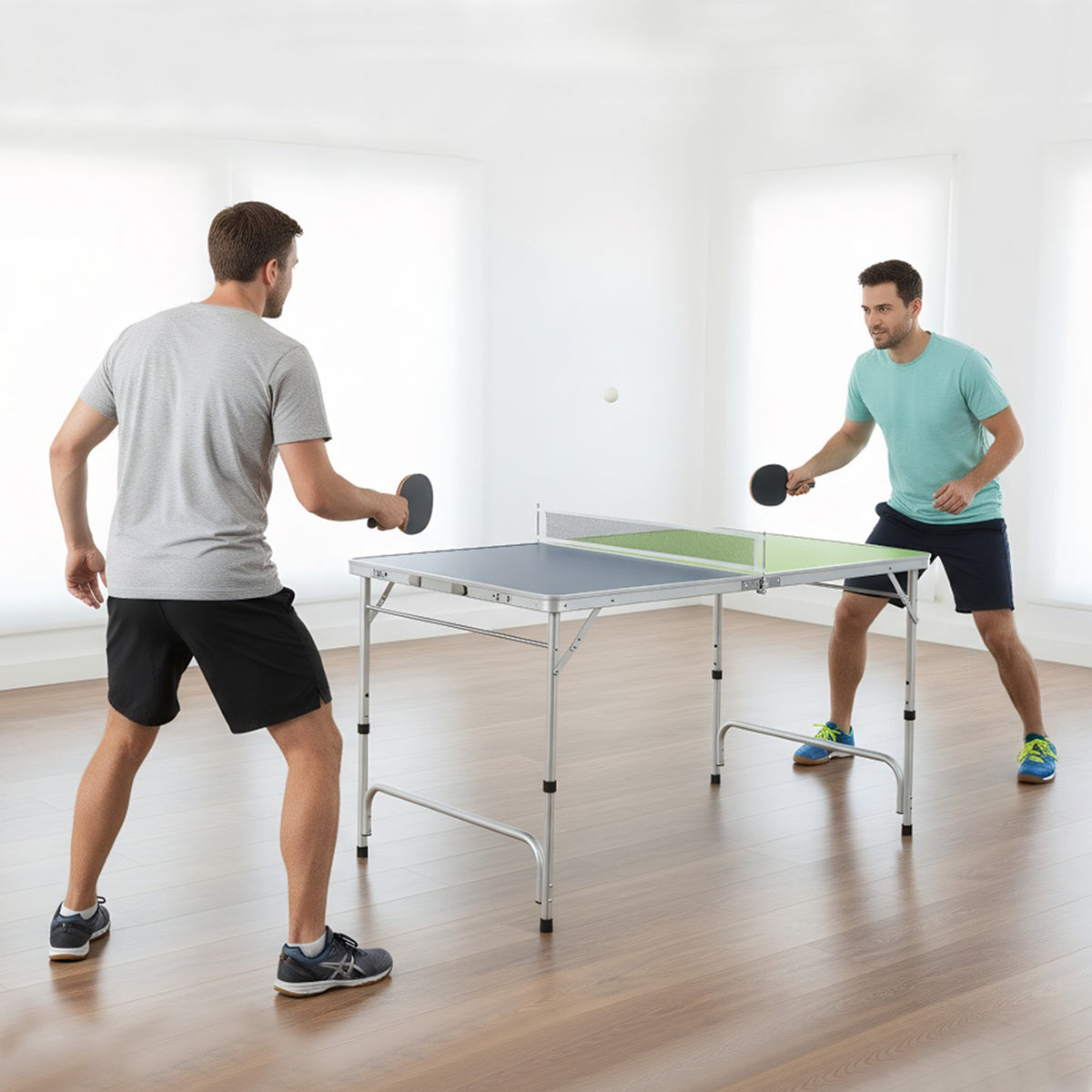 Two men playing table tennis in a bright room with the green and blue table