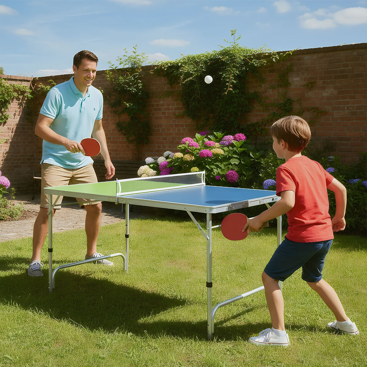 Father and son playing table tennis in a sunny garden with the green and blue table