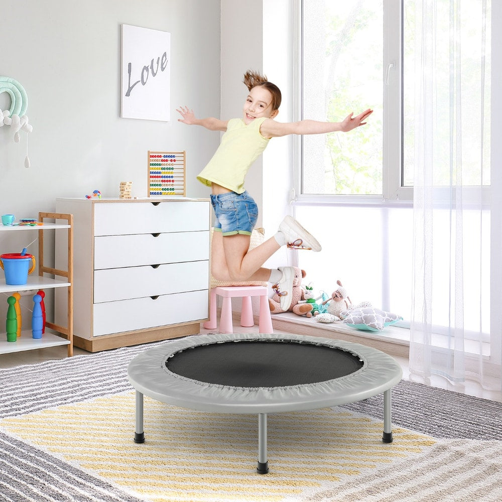 A young girl jumping on the grey foldable mini trampoline in a child's bedroom