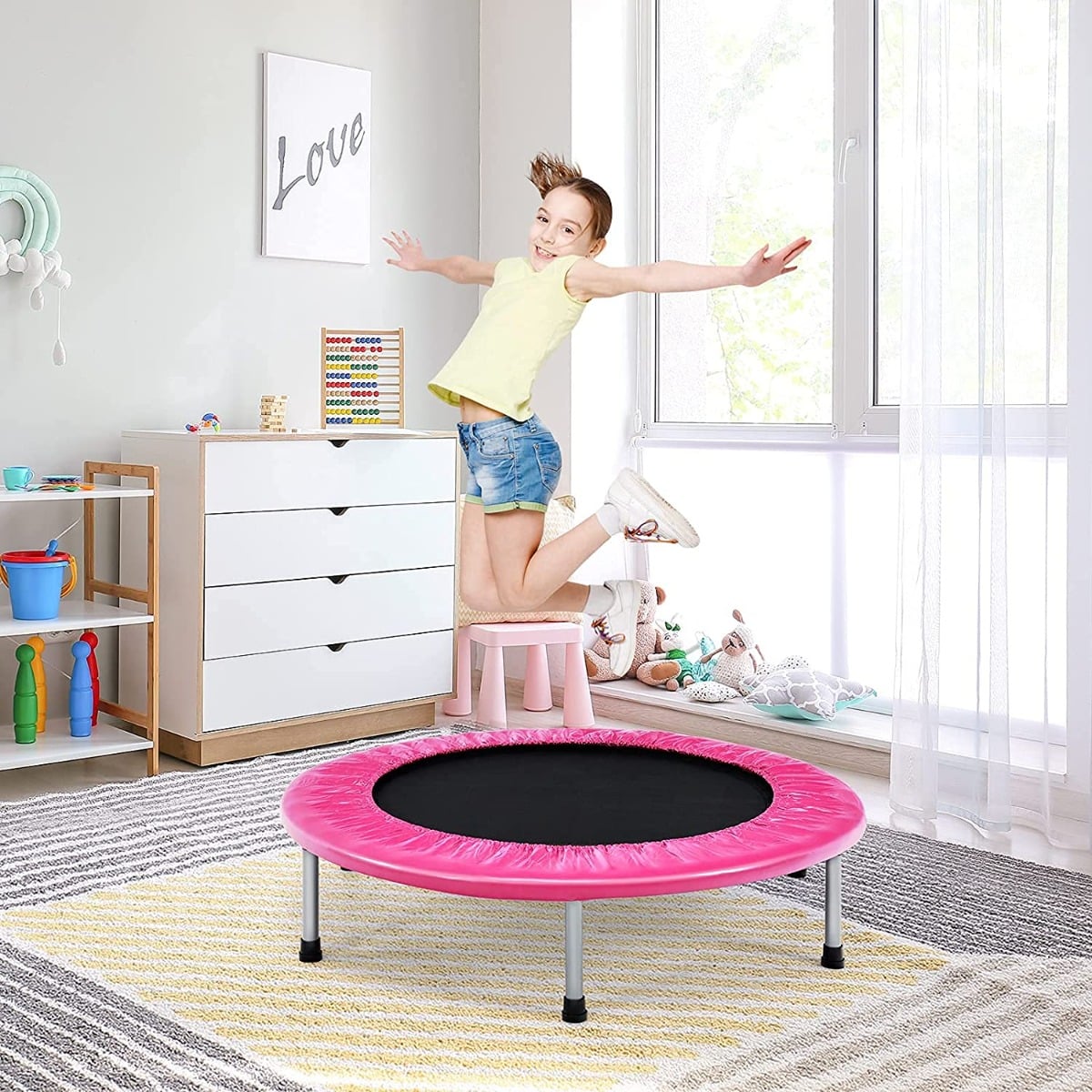 A child jumping on the pink mini trampoline in a child's bedroom
