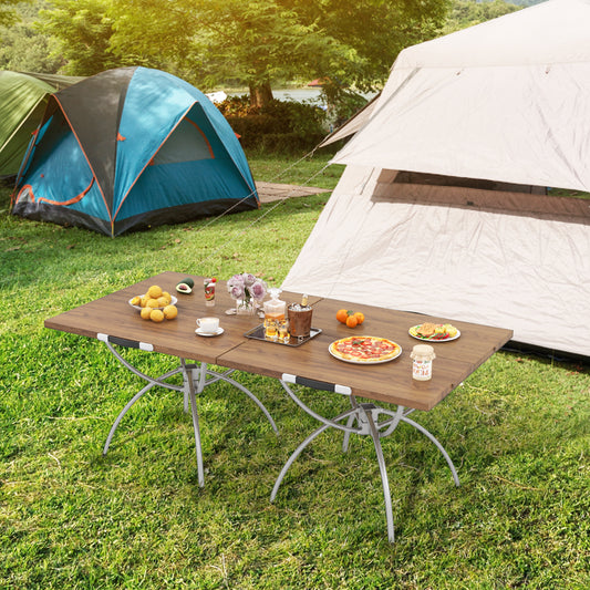 The camping table set up with food and drinks on a grassy lawn between two tents