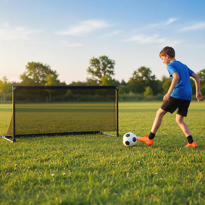 Boy kicking a soccer ball towards the pop-up goal on a grassy field