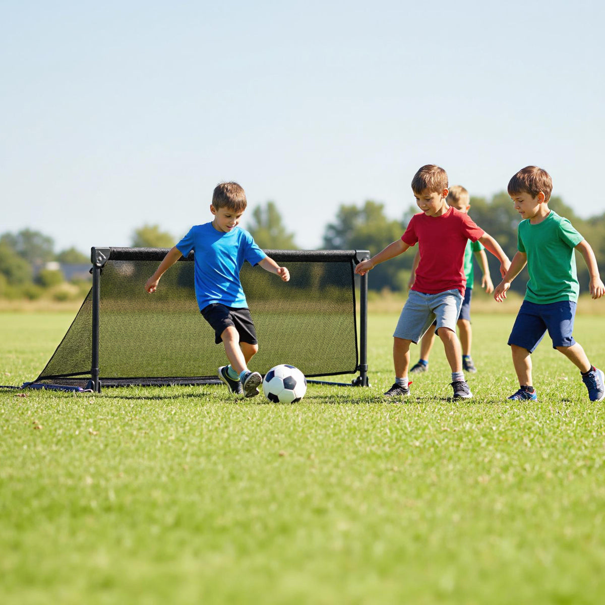 Children playing football with the pop-up soccer goal on a grass field