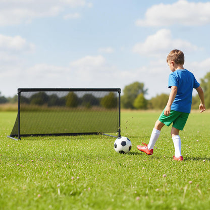 Boy kicking a soccer ball towards the goal on a lawn