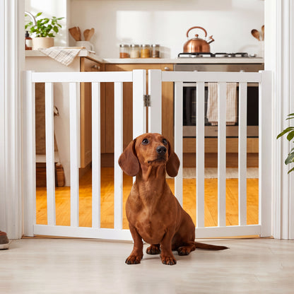 A dachshund sits in front of the white wooden pet gate, which is installed in a kitchen doorway