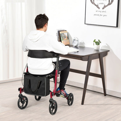 A man sits on the red walker with four wheels while working at a desk