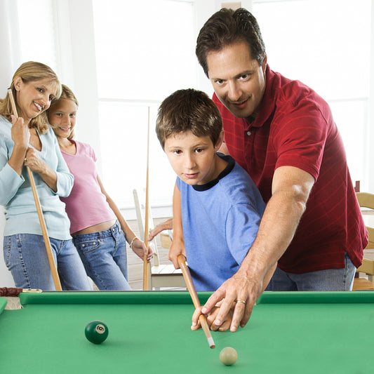 A family playing billiards together on the green folding table