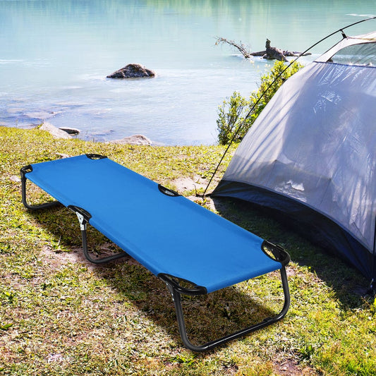 The camping furniture set up on grassy ground next to a tent by a lake