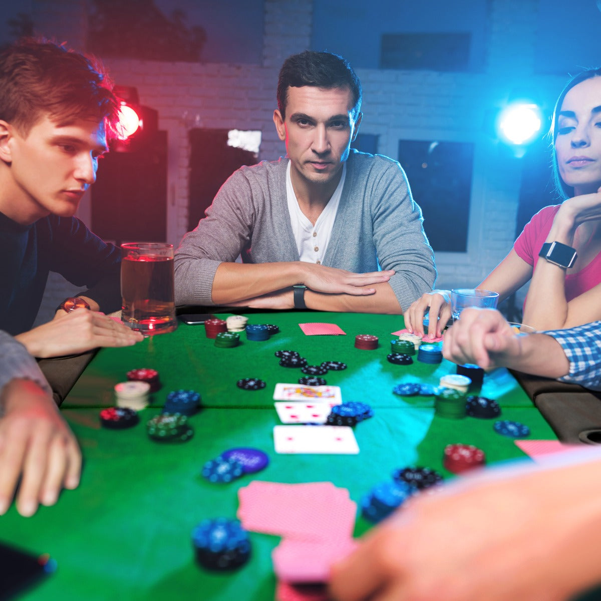 People playing cards and poker at the green game table, with drinks and chips