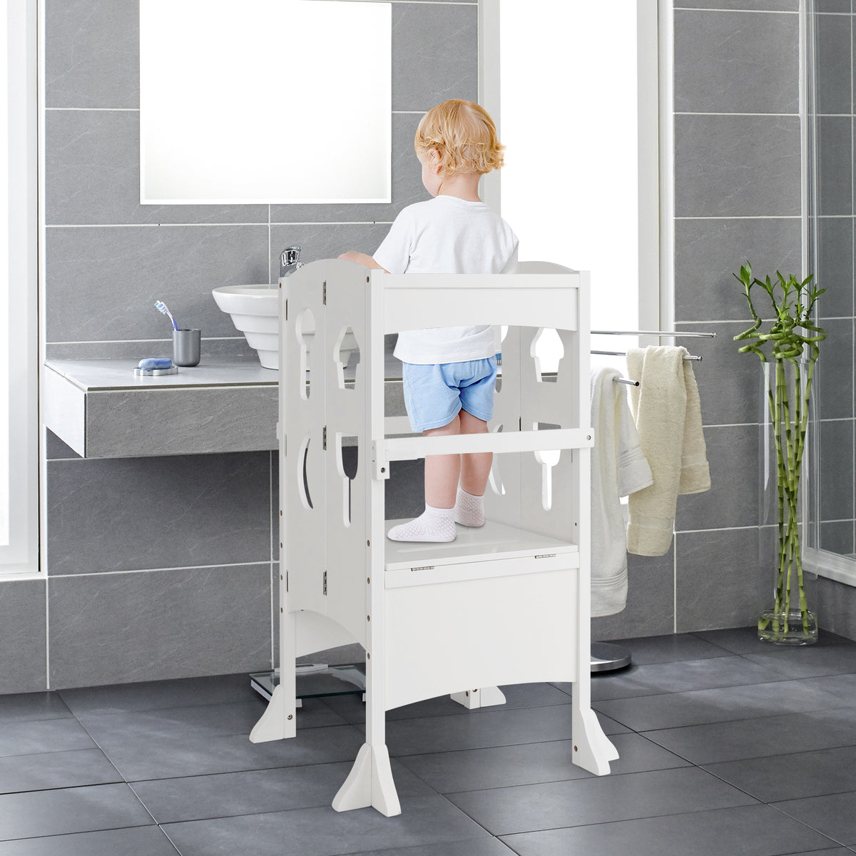 A young child standing on the white nursery furniture step stool in a bathroom