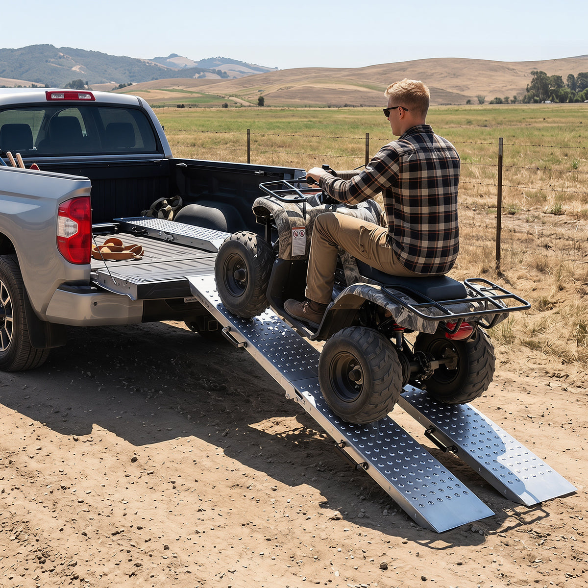 The metal ramps positioned against a pickup truck to help load a quad bike