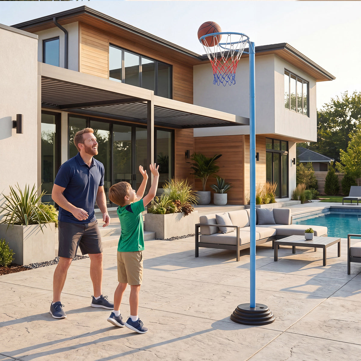 A father and son play basketball on a patio near a swimming pool