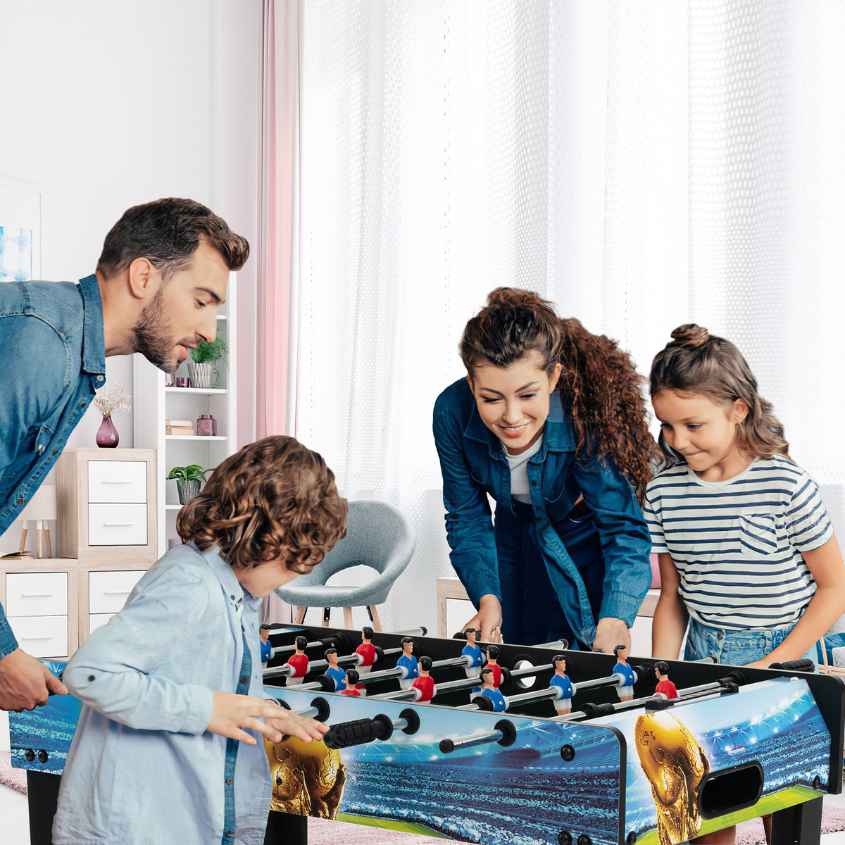 A family playing together on the football table in a bright living room
