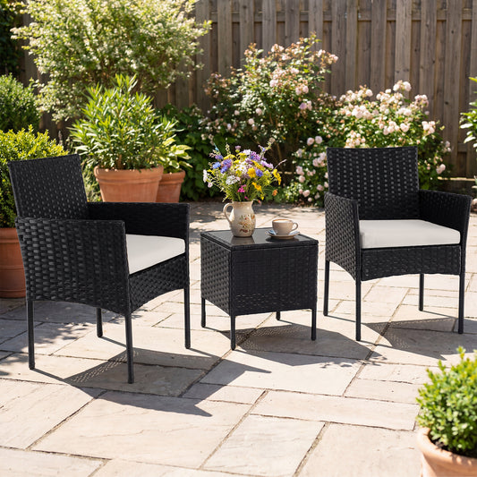 The rattan balcony furniture set with two cushioned chairs and a coffee table on a paved patio